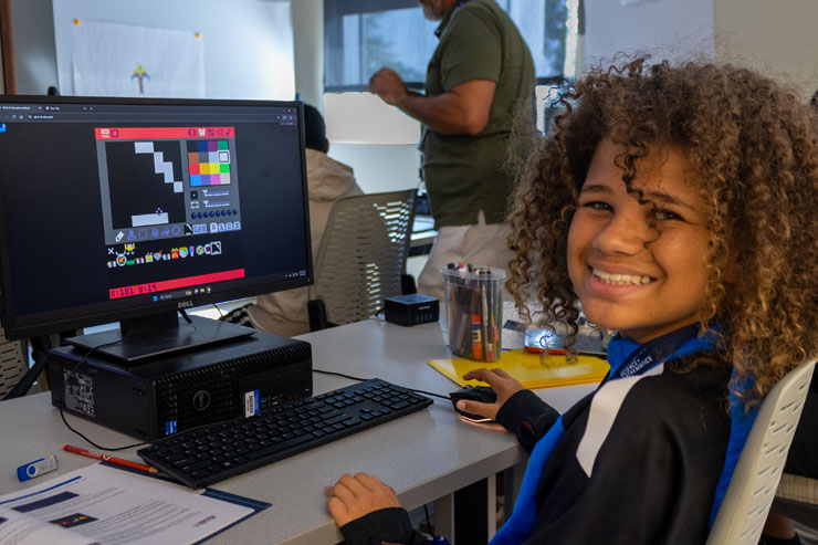 photo of student smiling while working at a computer