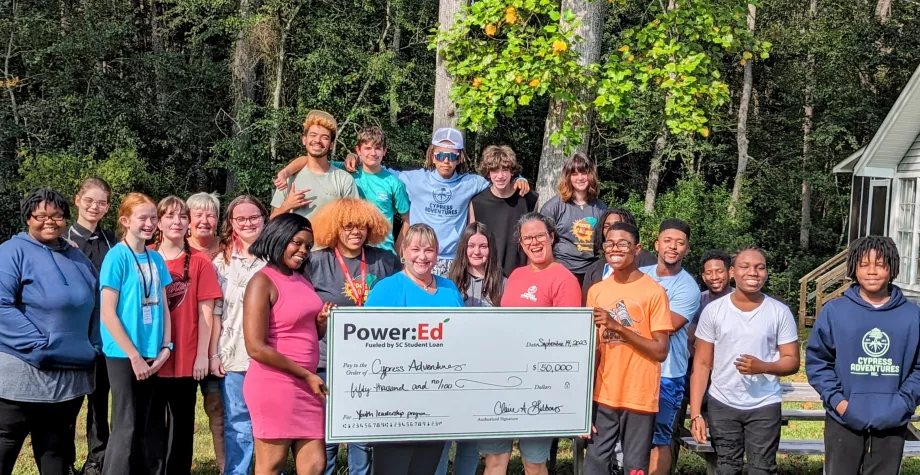 Youth and adults pose with ceremonial big check