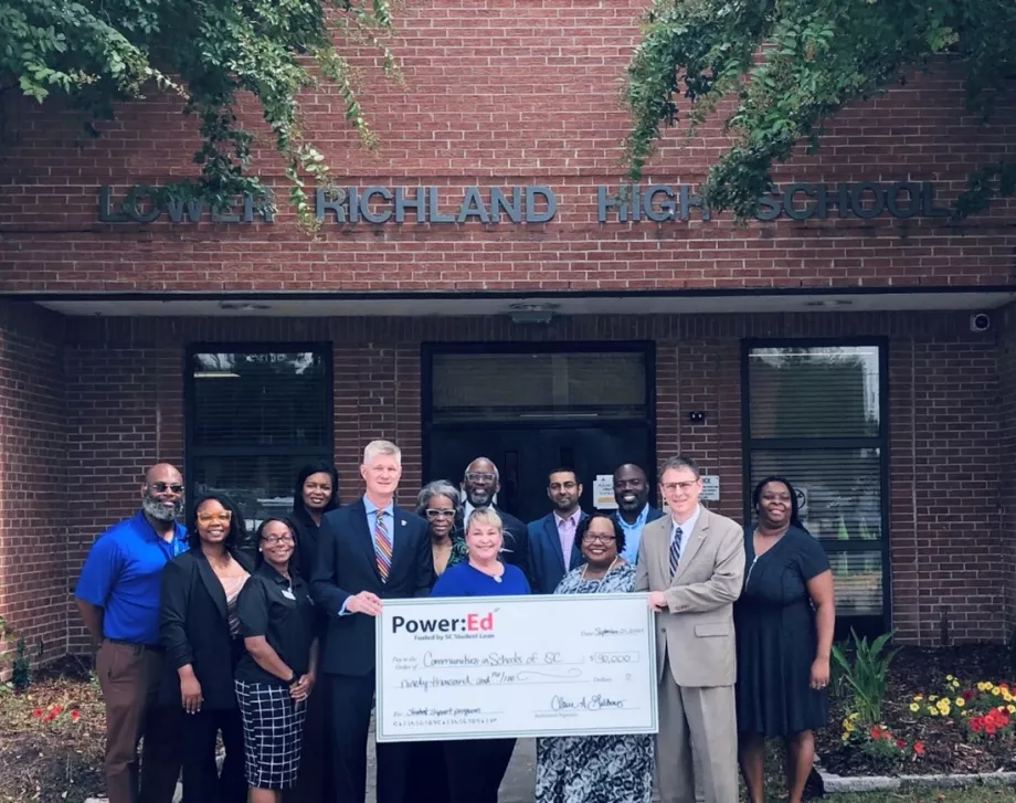 Executives pose with ceremonial check