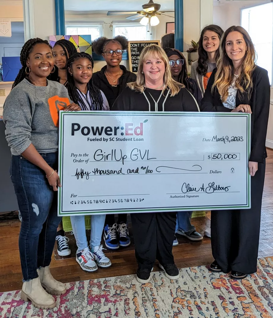 Women and girls pose with ceremonial check