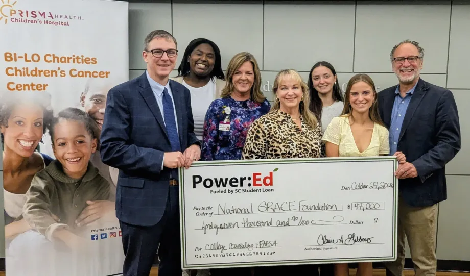 Executives and students pose with ceremonial big check