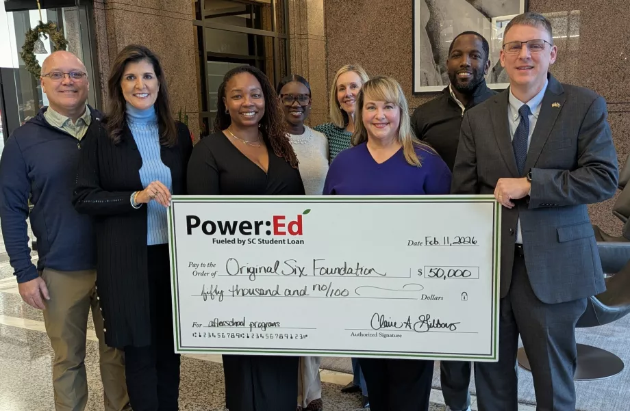 Executives pose with ceremonial big check
