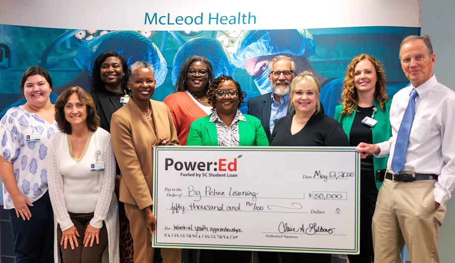 Executives pose with ceremonial big check