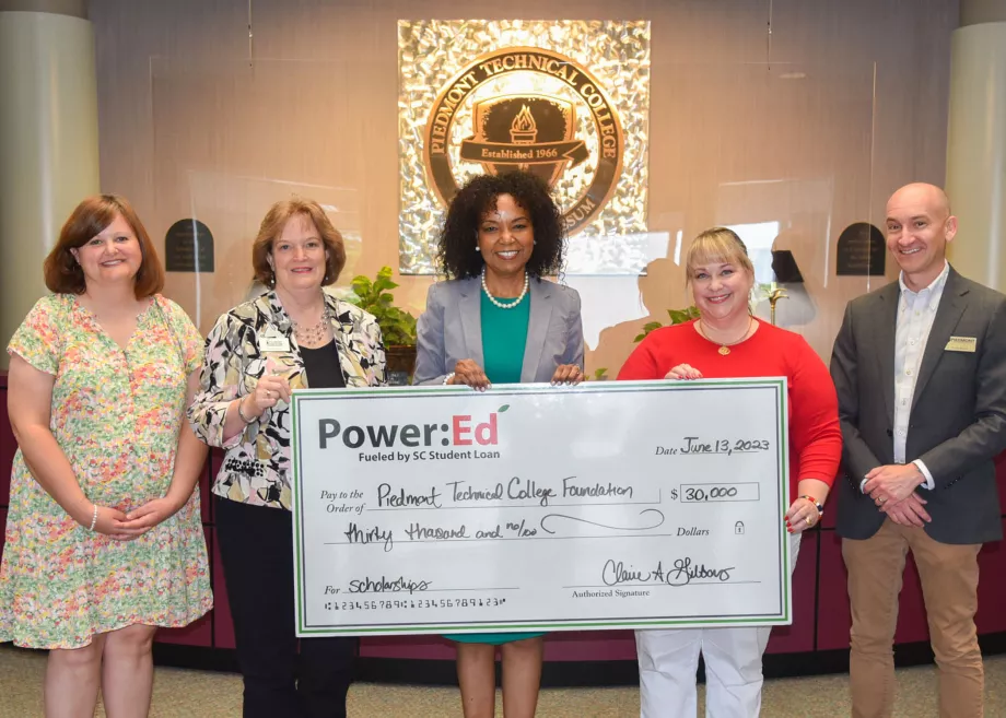 Executives pose with ceremonial check