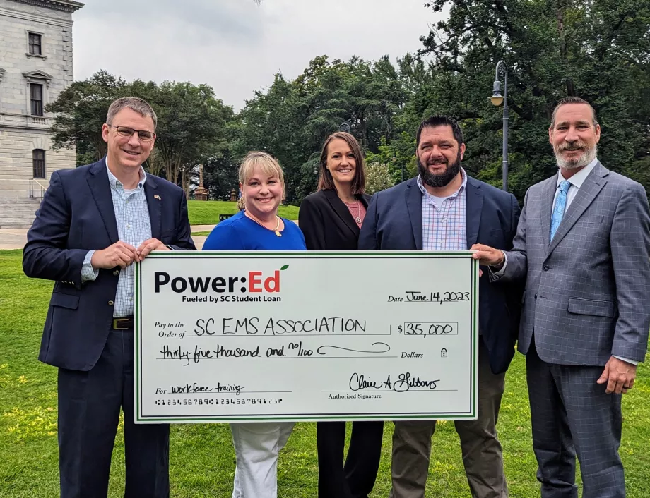 Executives pose with ceremonial check