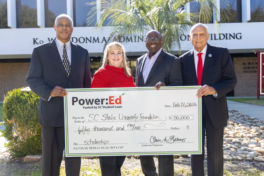 Executives pose with ceremonial big check