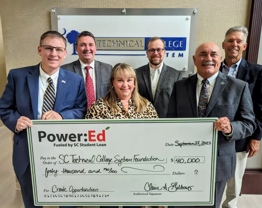 Executives pose with ceremonial check