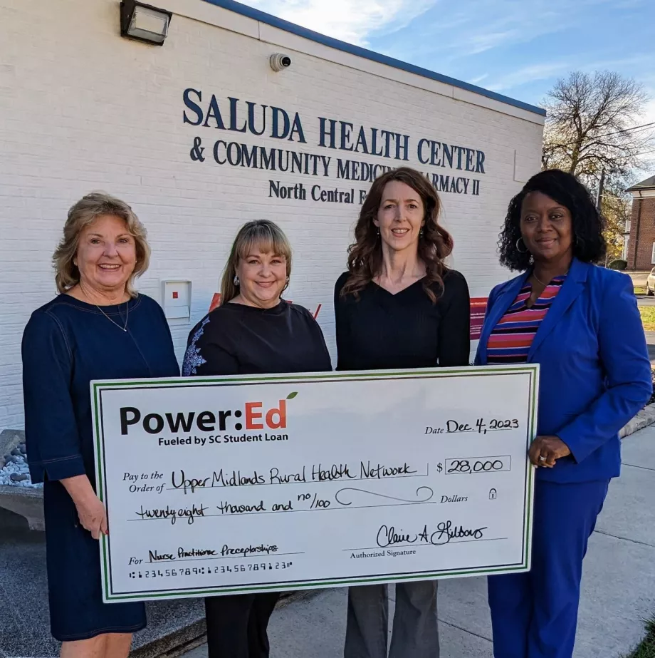 Women executives pose with ceremonial big check