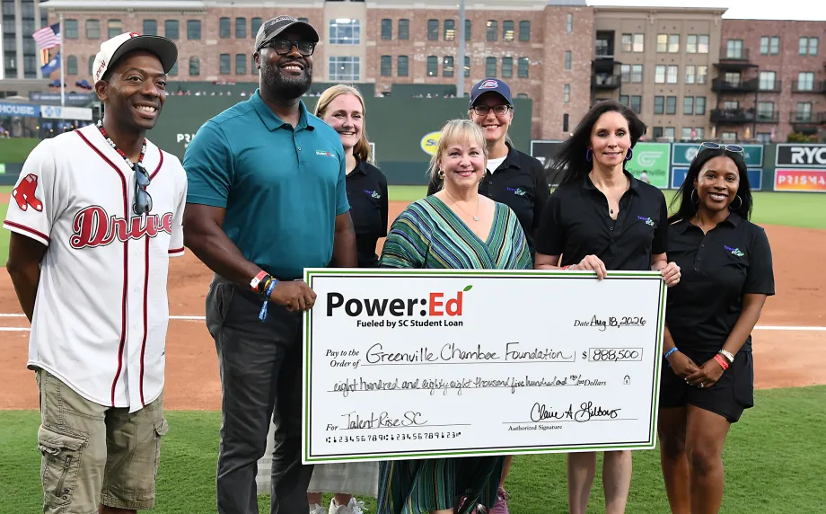Executives pose with ceremonial big check on baseball field